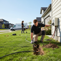 Professional installer laying in-ground sprinkler system pipes and heads